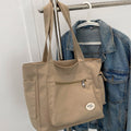 Tan canvas tote bag front pockets and zipper detail