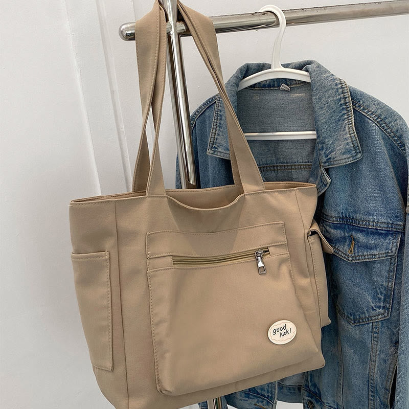 Tan canvas tote bag front pockets and zipper detail
