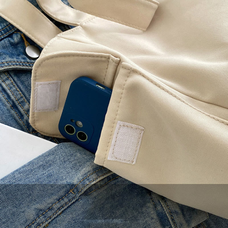 Ivory canvas tote bag side pocket holding a phone