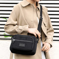 Black four-zip nylon crossbody bag worn at the front
