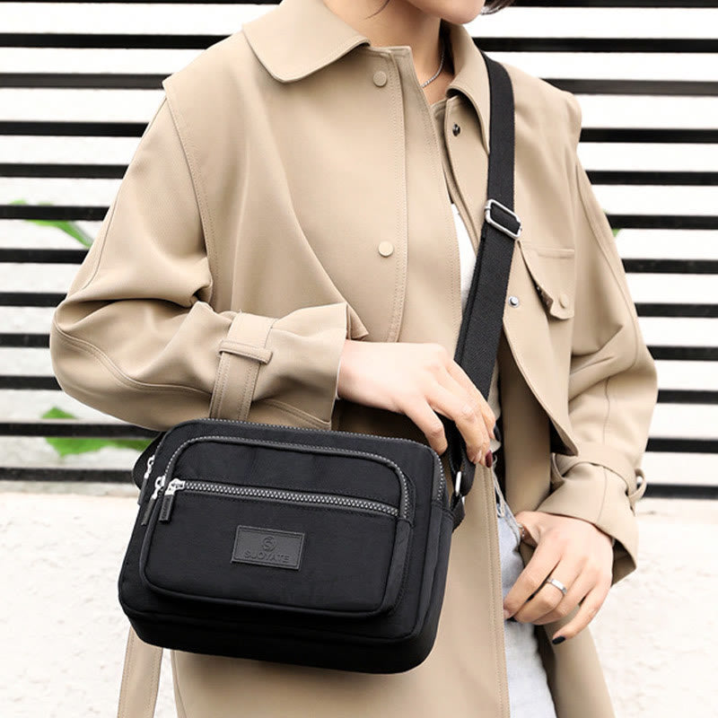 Black four-zip nylon crossbody bag worn at the front