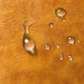 Water droplets on camel brown PU leather surface detail