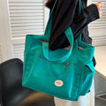 Mint green canvas tote bag held by the handles