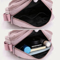 Light pink four-zip crossbody bag with open compartments and everyday items