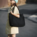 Black large canvas tote bag worn on the shoulder