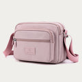 Light pink four-zip nylon crossbody bag angled front view