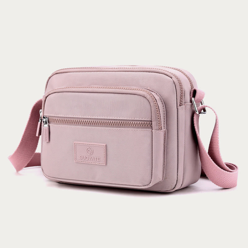 Light pink four-zip nylon crossbody bag angled front view