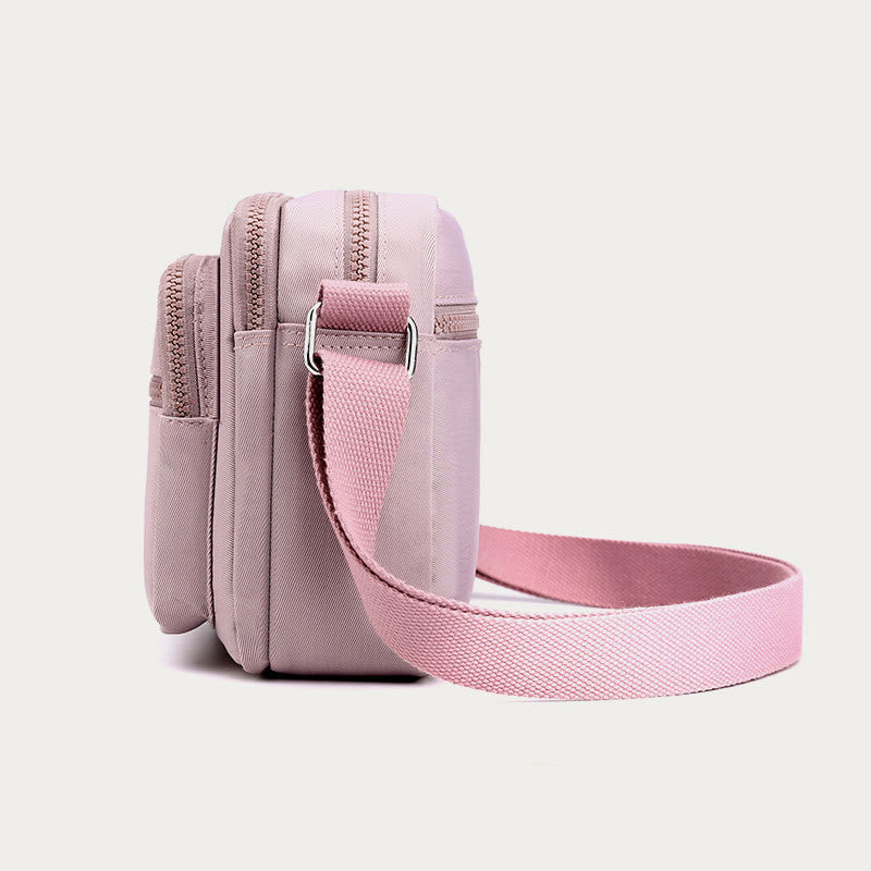 Light pink four-zip crossbody bag side view with adjustable strap