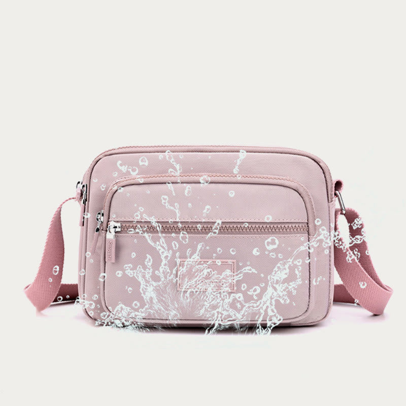 Light pink four-zip nylon crossbody bag front pocket detail