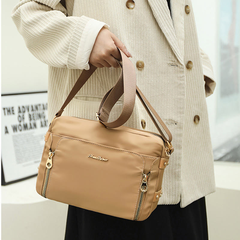 Cream waterproof nylon crossbody bag carried by the top handles