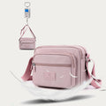 Light pink four-zip crossbody bag hanging from its adjustable strap