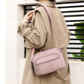 Light pink four-zip nylon crossbody bag worn at the hip
